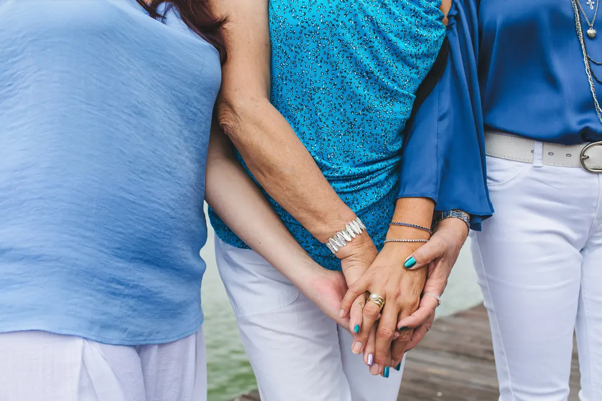 Three people holding hands outdoor by water